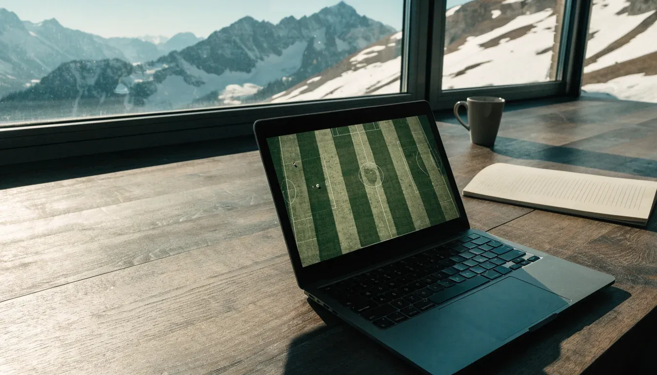 Schneebedeckte Berggipfel erheben sich im klaren Morgenlicht hinter einem leeren Stadion mit hellen Zuschauerrängen.